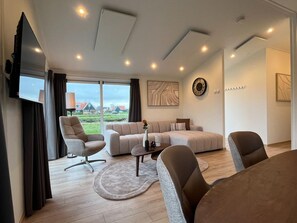 Una sala de estar moderna con un sofá, una mesa de centro y un televisor instalado en la pared.