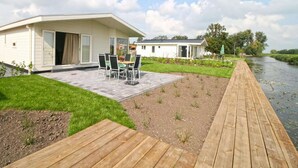 Une maison moderne dotée d’un patio, d’une terrasse en bois et offrant une vue sur la rivière.