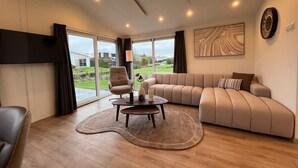 Un salon moderne avec un canapé, un fauteuil, une table basse et une vue dégagée grâce à de grandes fenêtres.