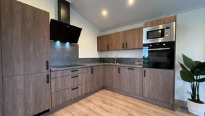 Une cuisine moderne avec des meubles en bois, un four à micro-ondes en acier inoxydable et un four encastré.