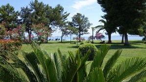 A well-maintained outdoor area with a grassy lawn, several trees, and a view of the sea. - Nafsika Beach (Delphi)