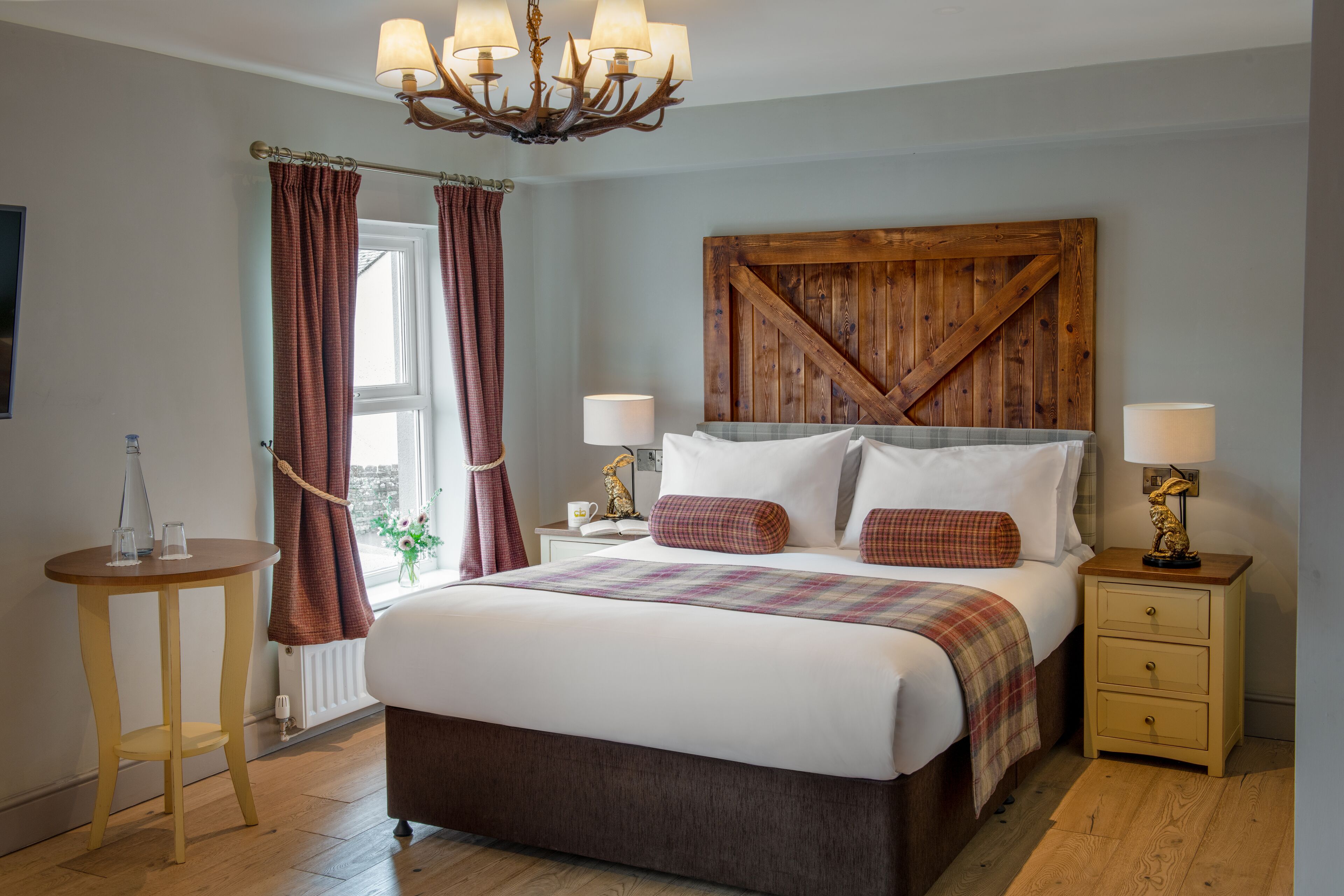 Camera da letto con un letto grande, una testiera in legno, un comodino con una lampada e un tavolino con un vaso.
