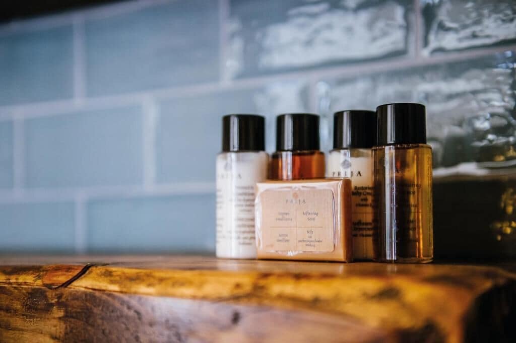 A set of skincare products on a wooden surface with a tiled wall in the background.
