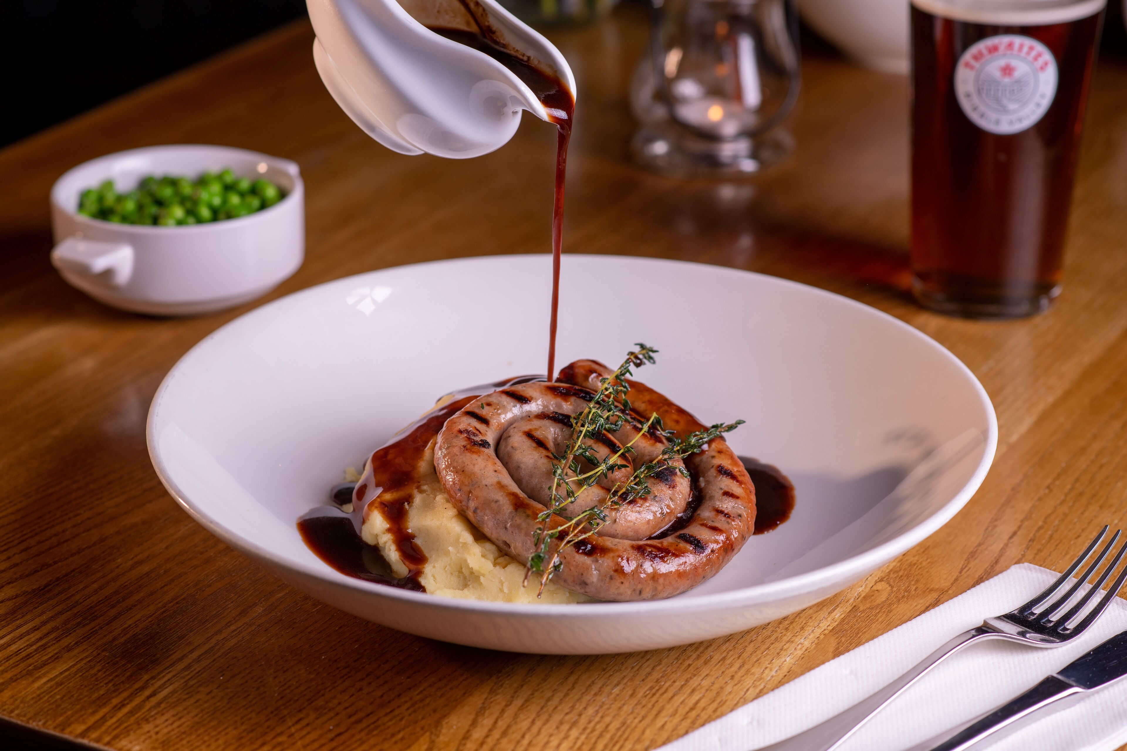 A plate with a sausage, mashed potatoes, and gravy.