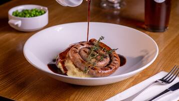 A plate with a sausage, mashed potatoes, and gravy.