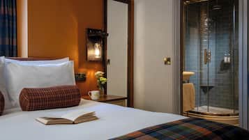 Hotelkamer met een bed, nachtkastje met een boek en mok, spiegel en douche met glazen deuren.