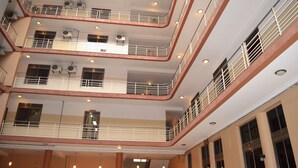 Un atrio de varios niveles con balcones, unidades de aire acondicionado y luces colgantes.