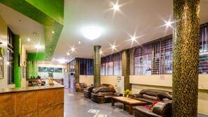 Un hall con mostrador de recepción, sofás de cuero, una mesa de centro y un pilar grande.