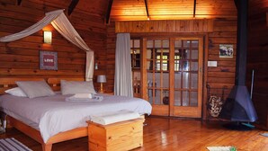 Une chambre confortable dans un chalet en bois, avec un lit, une table de chevet et une cheminée.