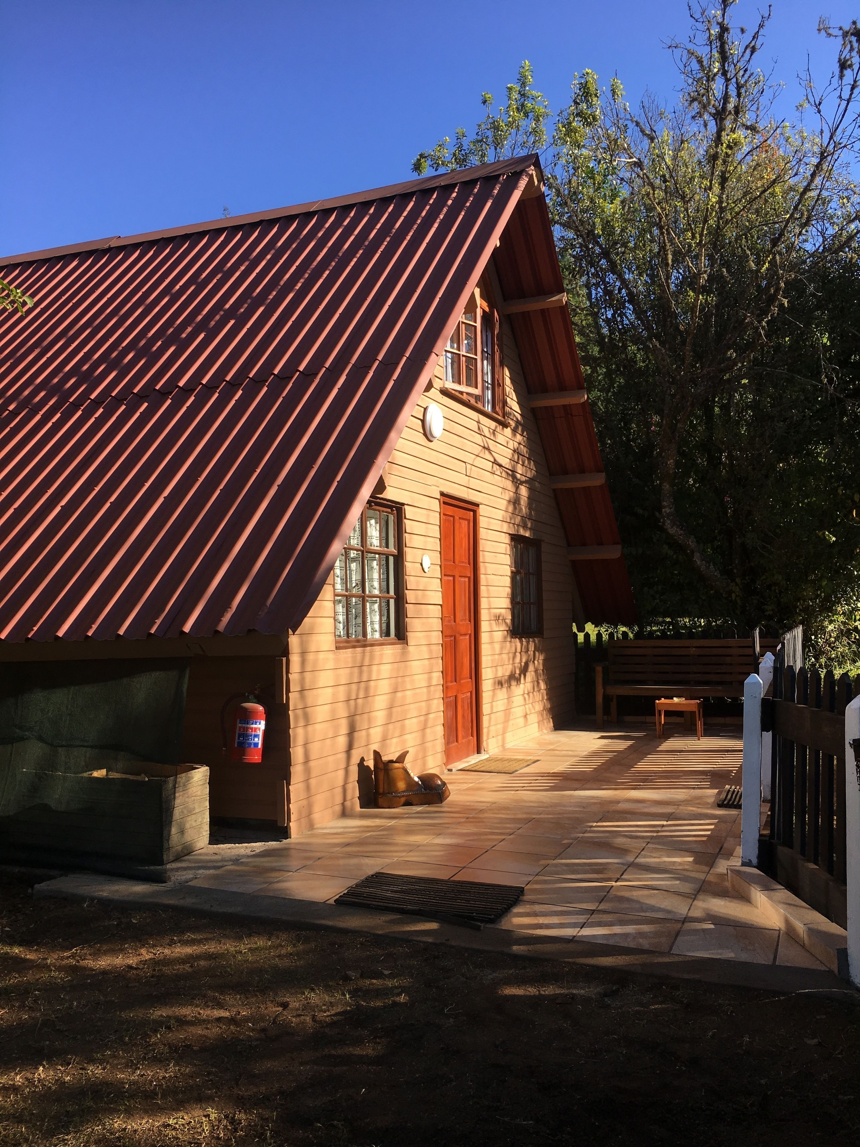 A rustic building with a sloped metal roof, a wooden door, and a fire extinguisher mounted on the wall.