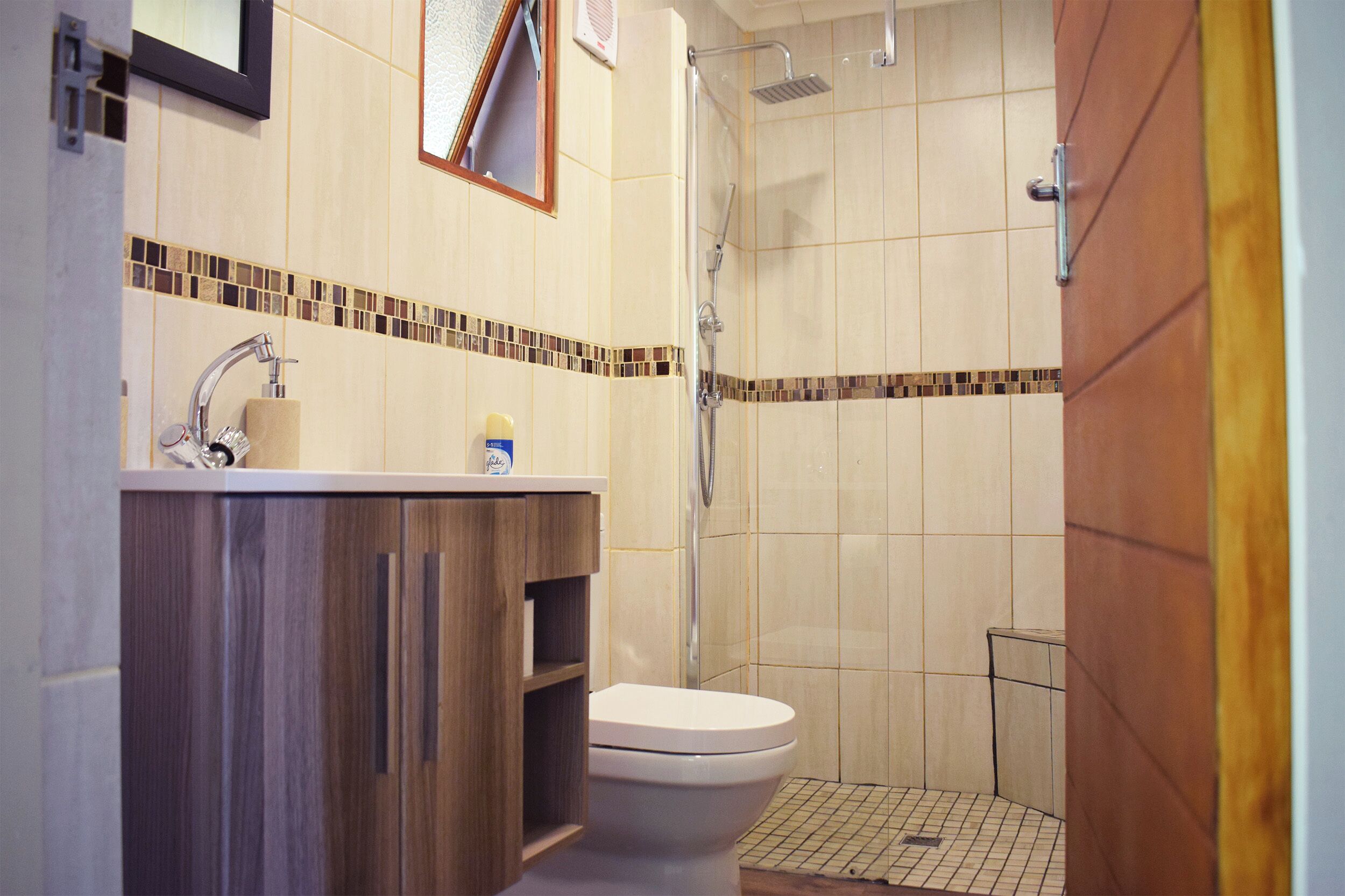 A bathroom with a wooden vanity, a toilet, and a shower area.