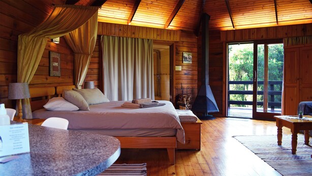 Une chambre dans un chalet en bois, avec un lit, une table et une cheminée.