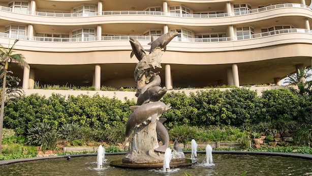 A multi-story hotel with a central courtyard featuring a dolphin sculpture and a fountain. - 302 Oyster Schelles (Umhlanga)