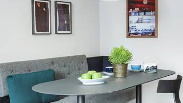 A modern dining area with a grey sofa, a round table, and a potted plant.