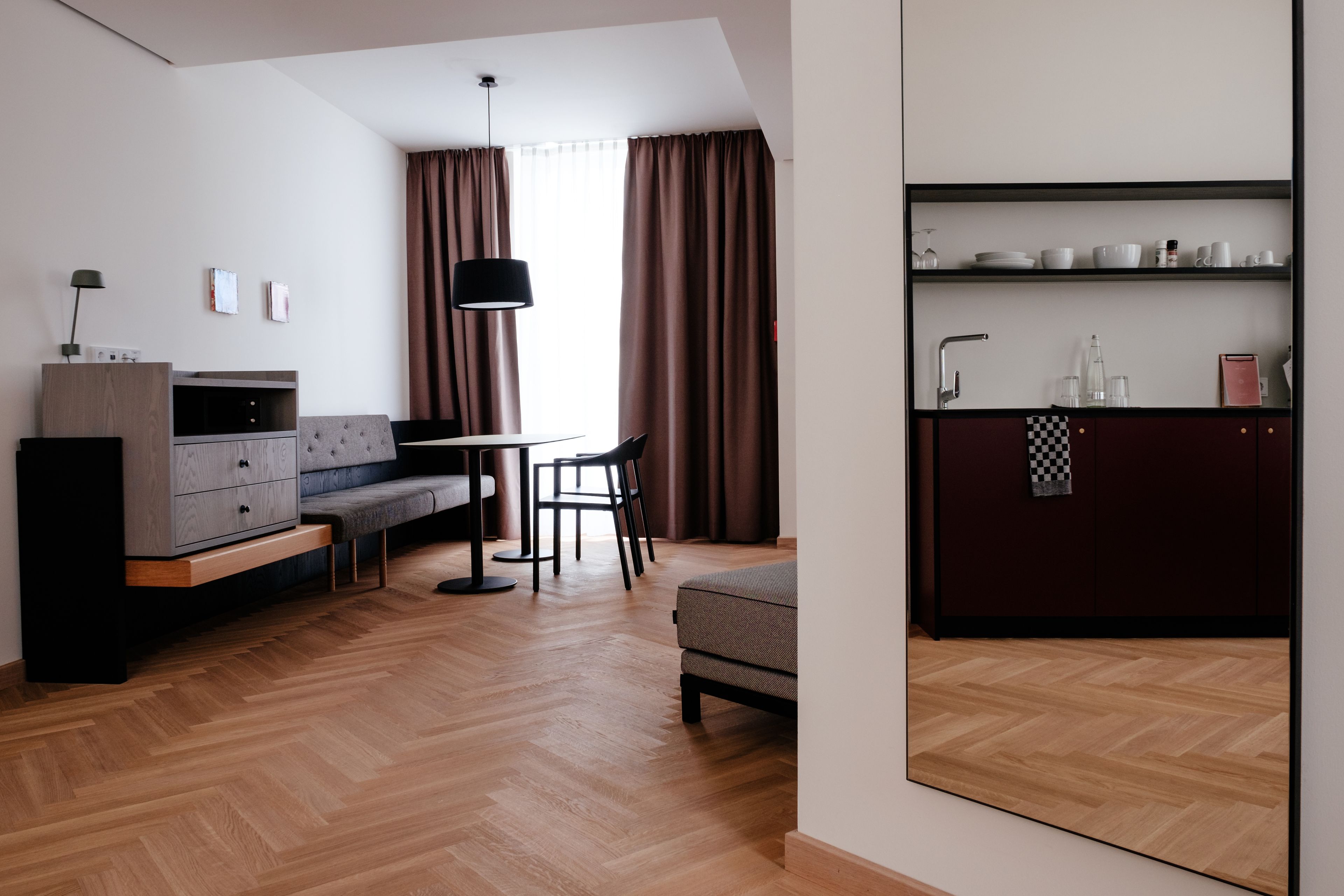 Una sala de estar moderna con un sofá, una mesa de comedor y una zona de cocina con estanterías.