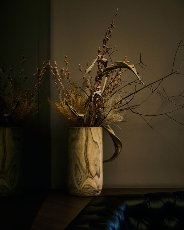 A vase with branches and dried flowers on a wooden surface. - Melter Hotel & Apartments (Nuremberg)