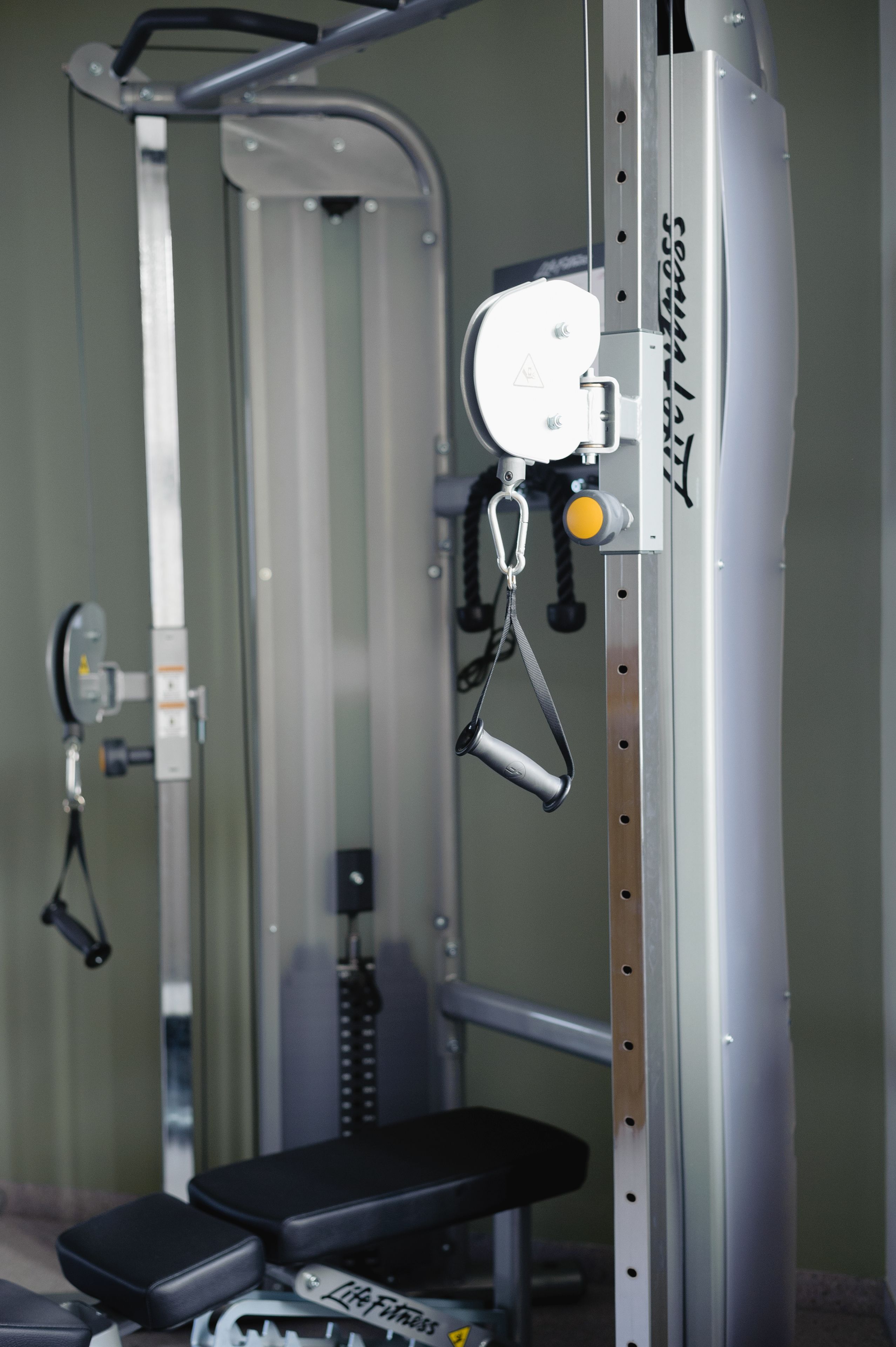 A gym with a bench, weight machine, and exercise equipment.