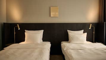 A hotel room with two single beds, a dark wood headboard, and two bedside lamps.