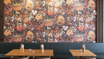 Ein Restaurant mit Wandmalerei mit floralem Dekor, Holztischen und gepolsterten Sitzgelegenheiten.