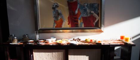 Un buffet de petit-déjeuner proposant divers plats et une peinture accrochée au-dessus.