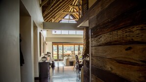 Un vaste hall d’entrée doté d’un plancher en bois qui mène à un balcon offrant une vue sur l’extérieur.
