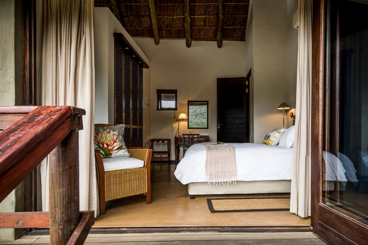 A bedroom with a bed, a chair, a desk, and a lamp.