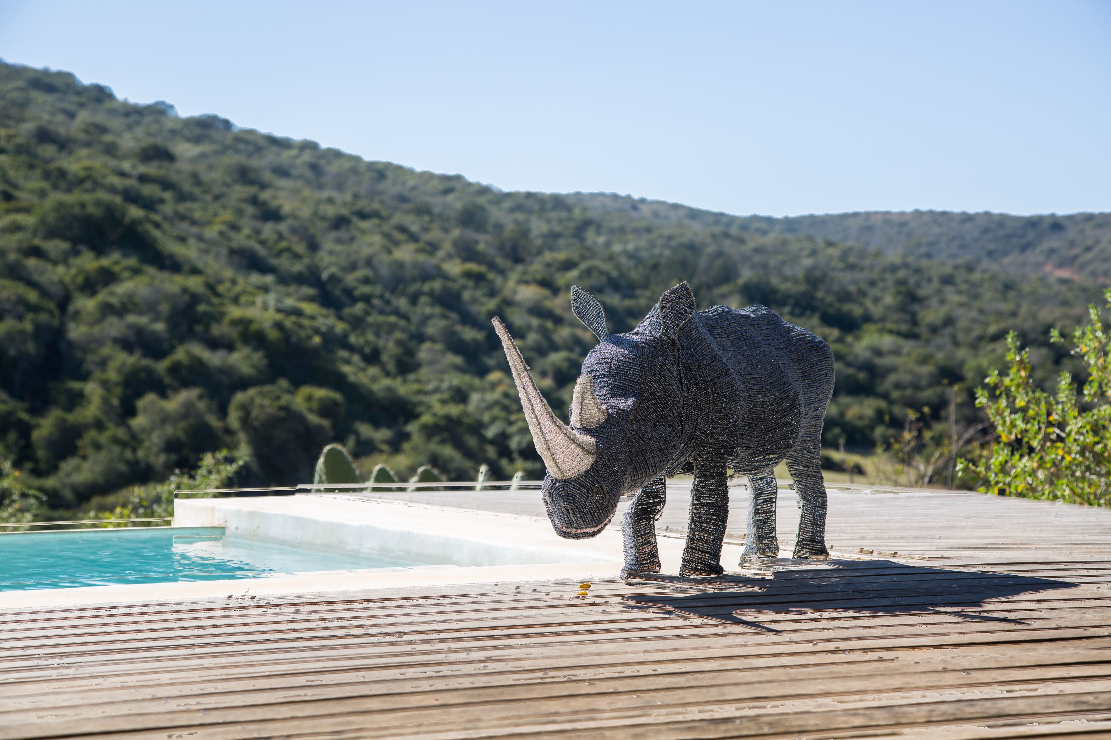 A wooden deck with a pool and a sculpture of a rhinoceros.