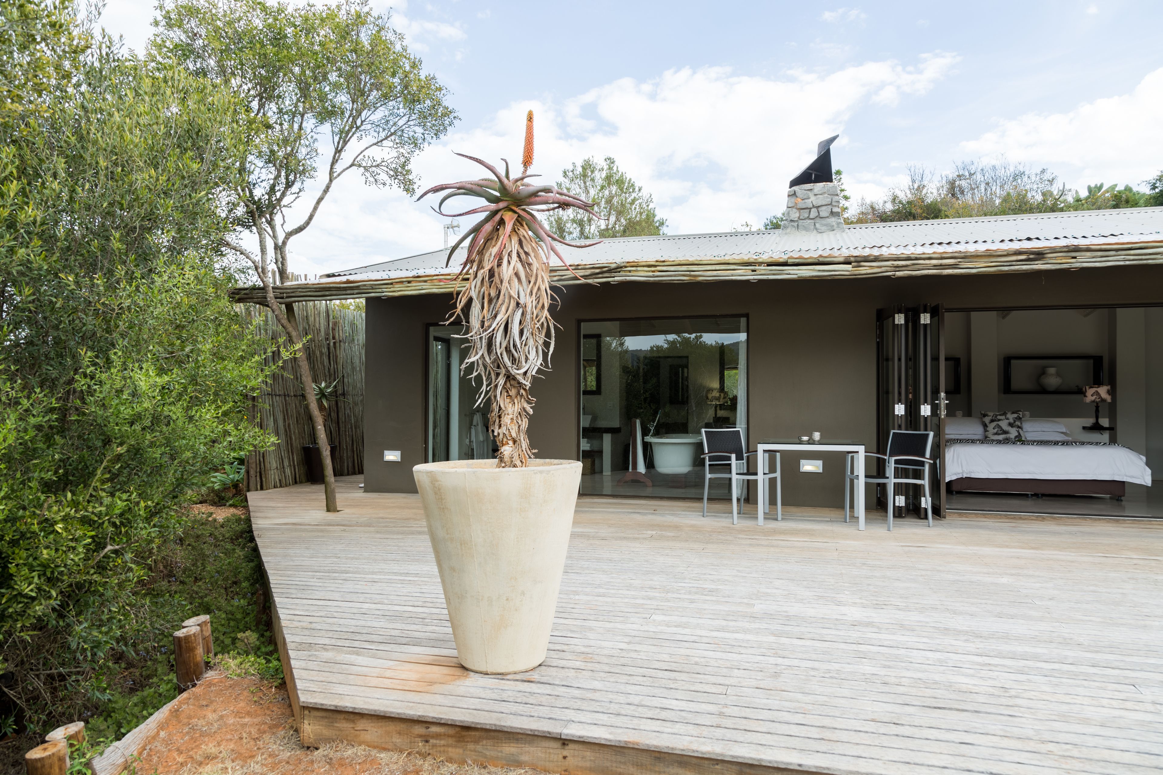 A modern house with a large planter, a deck, and a bedroom with a bed and a chair.