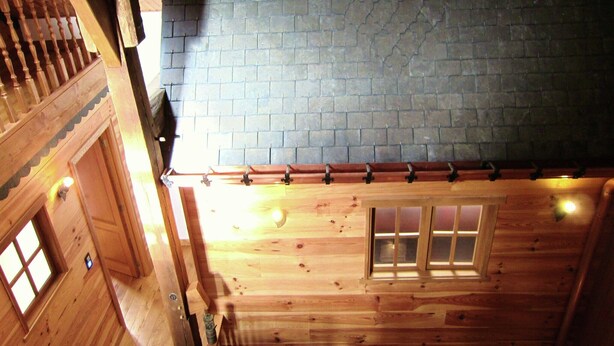 A wooden cabin with a sloped roof, a wooden staircase, and a brick wall.