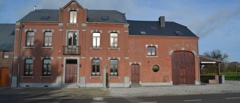 Un bâtiment en briques rouges, doté d’une façade symétrique, de nombreuses fenêtres et d’une entrée centrale.