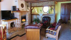 A cozy living room with a fireplace, leather sofas, a television, and a brick ceiling.