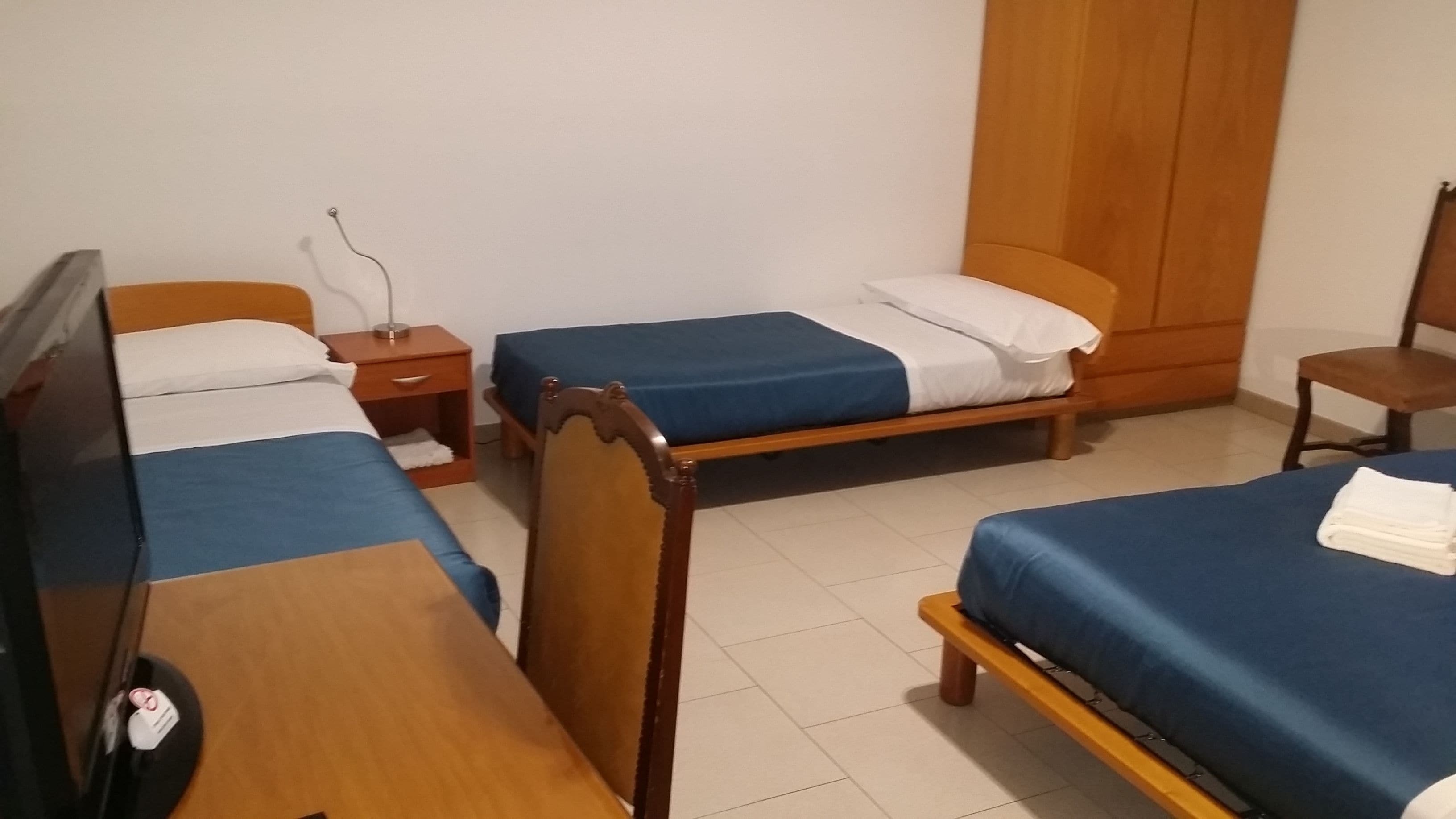 A room with two single beds, a wooden desk, and a chair.