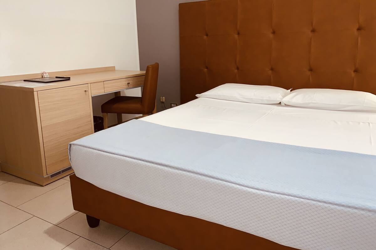 A hotel room with a bed, a desk, and a chair.