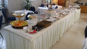 Montaje de bufé con diversos alimentos y utensilios para servir.