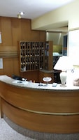 Uma mesa de recepção com balcão de madeira, uma luminária branca e uma escultura de peixe.