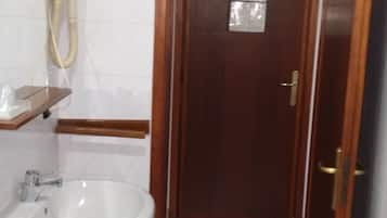 A bathroom with a white sink, a mirror, and a wooden door.