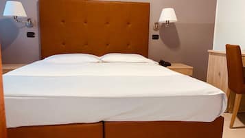 A double bed with a tufted headboard, two bedside lamps, a nightstand, and a wooden chair.