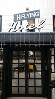 Exterior de um hotel com uma placa que diz 'FLYING Hotel'.