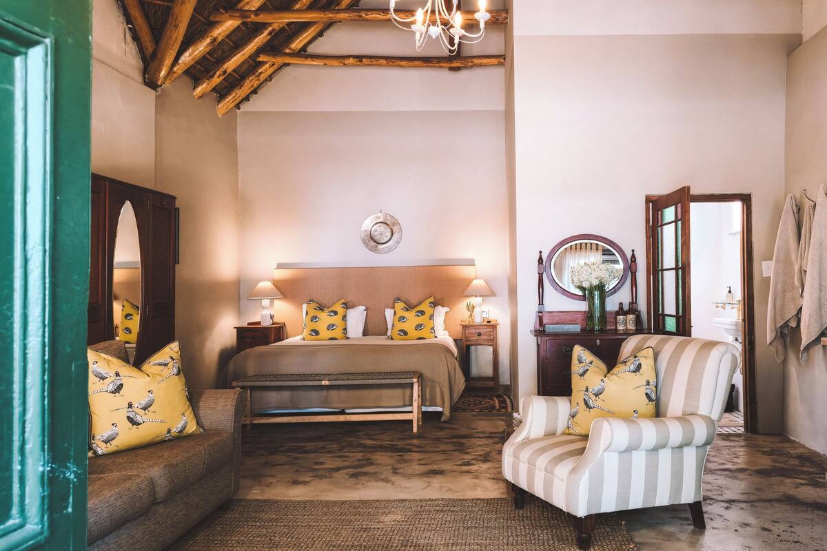 A cozy bedroom with a bed, a chair, a dresser, and a mirror.