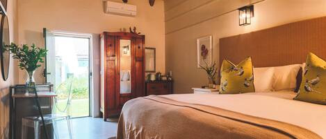 A bedroom with a bed, bedside tables, a mirror, a wooden wardrobe, and a door leading to an outdoor area.