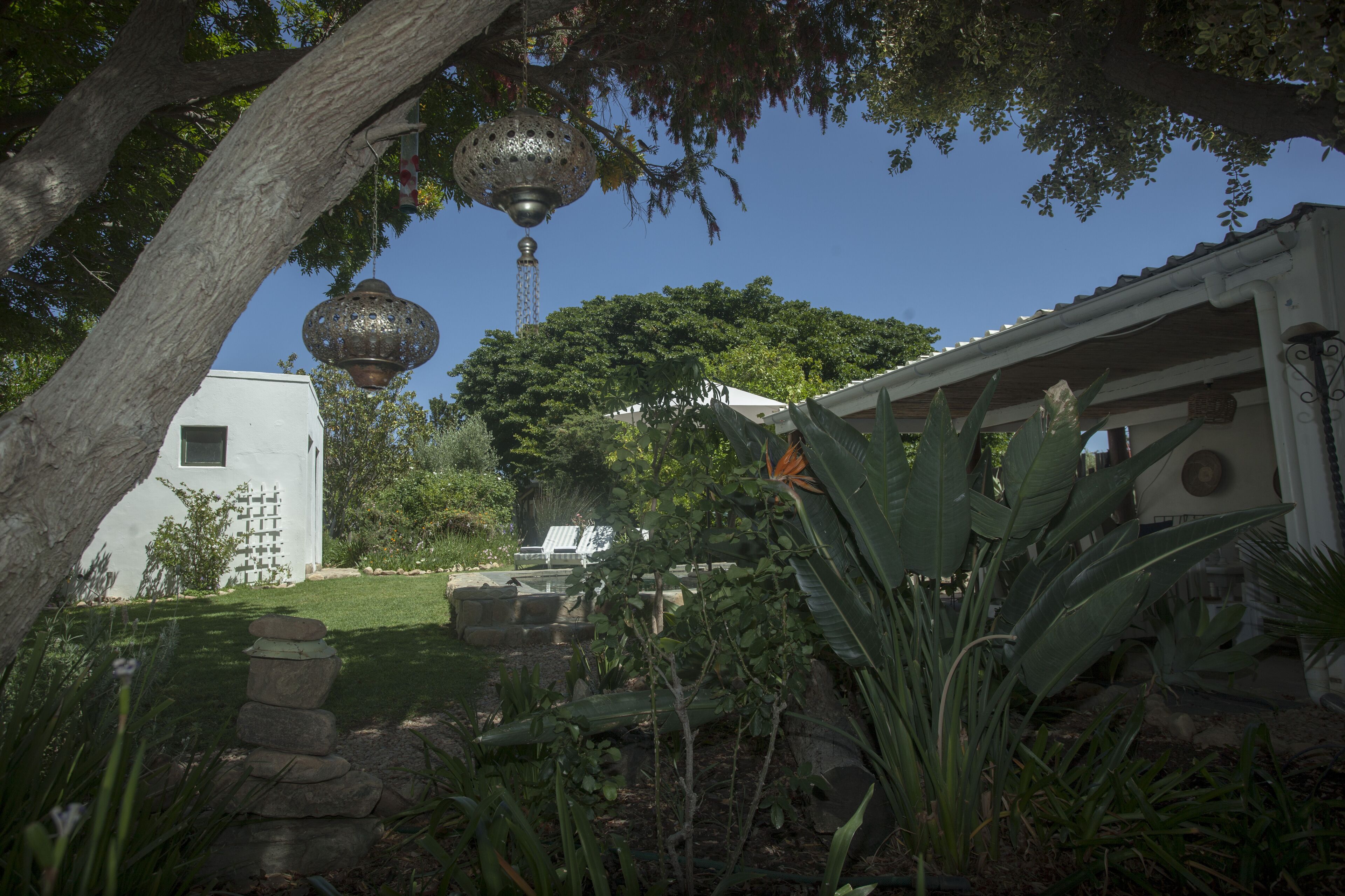 Un jardin avec un bâtiment blanc, une lanterne suspendue et un arbre.