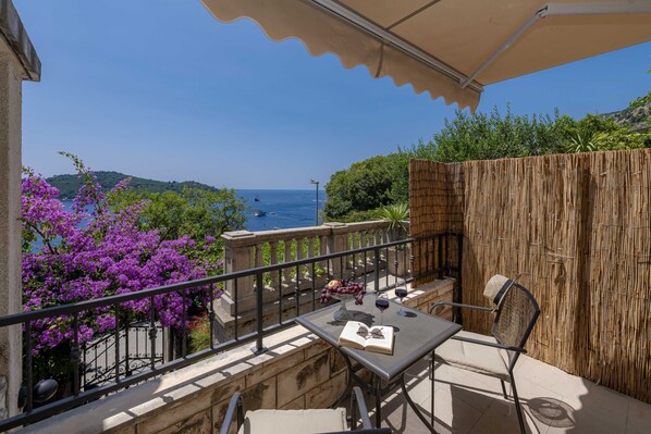 A balcony with a table, chairs, and a view of the sea. - Apartments Kirigin (Dubrovnik)