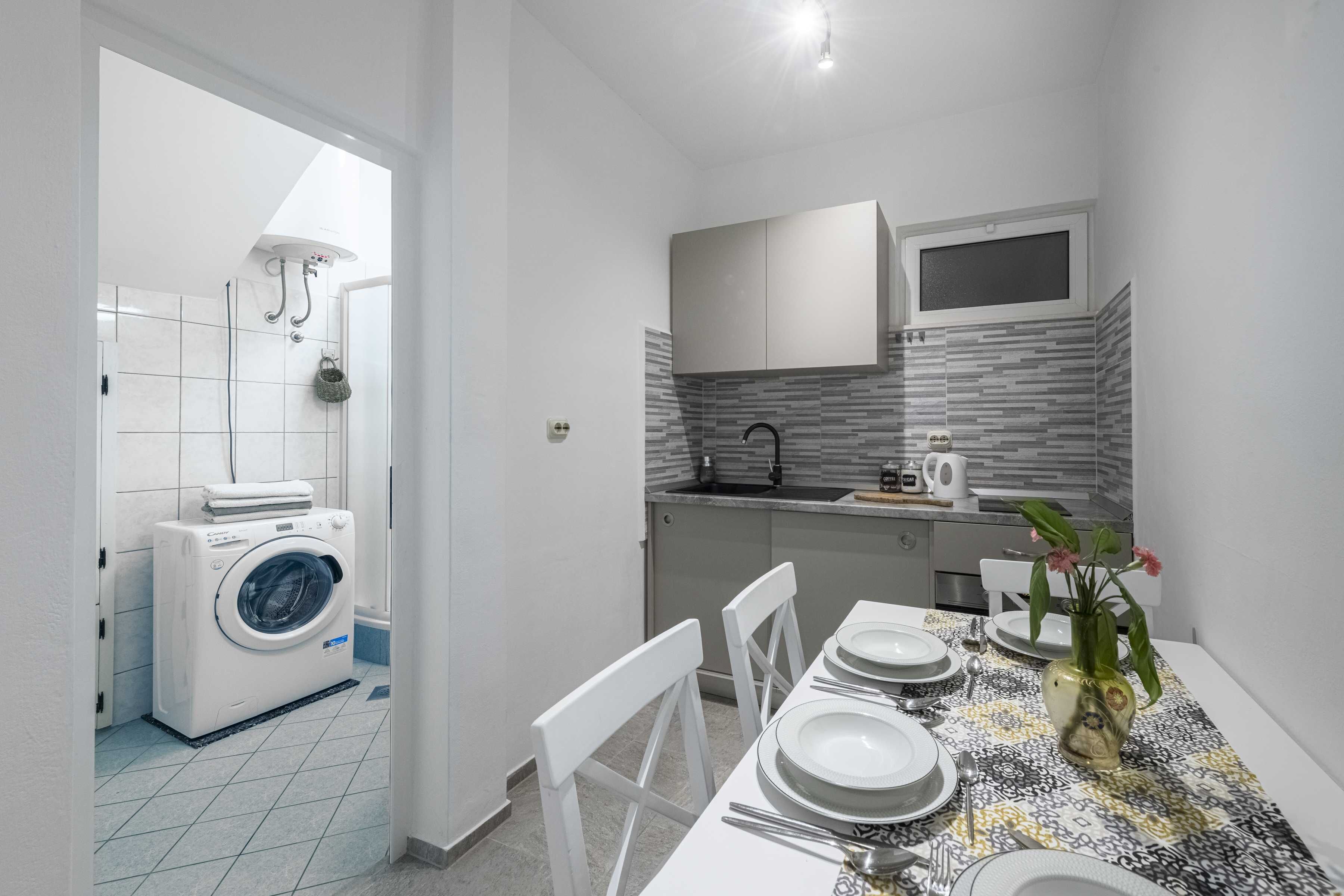 Una cocina compacta con microondas integrado, un lavamanos y una ventana sobre la encimera.