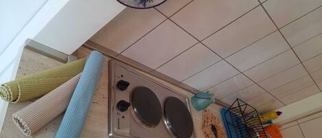 Una cocina con estufa, un hervidor azul y un escurreplatos.