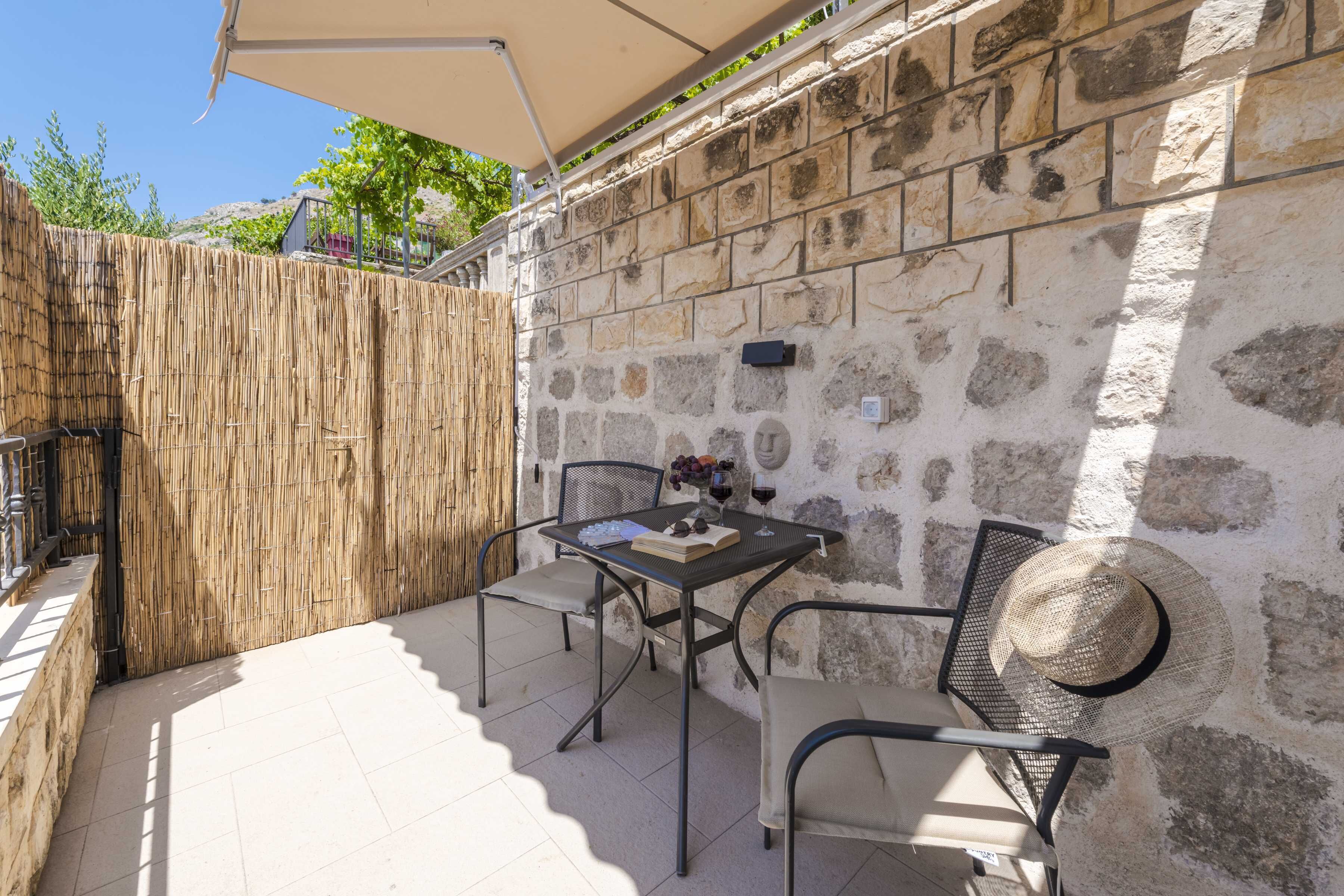 Un patio con una mesa, sillas y un sombrero de paja sobre la mesa.