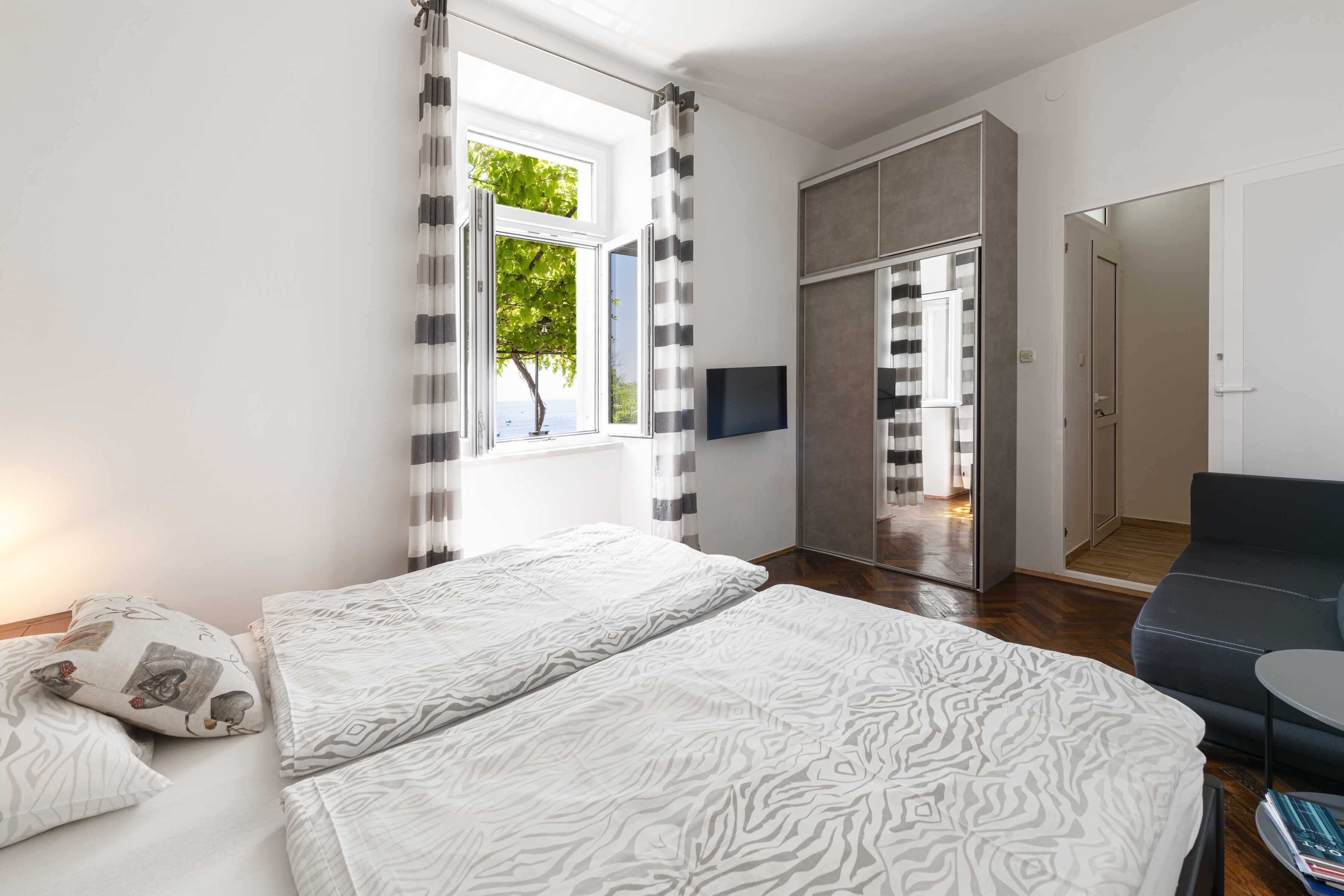 Una habitación de hotel moderna con una cama grande, un sofá, un televisor y una puerta corrediza que da al baño.