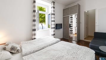 Una habitación de hotel moderna con una cama grande, un sofá, un televisor y una puerta corrediza que da al baño.