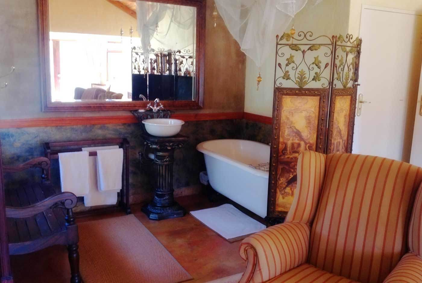 Un baño con bañera, lavabo, espejo y una silla.