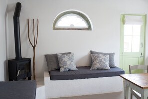 A cozy room with a built-in bench, a small window, a green door, and a wood-burning stove.