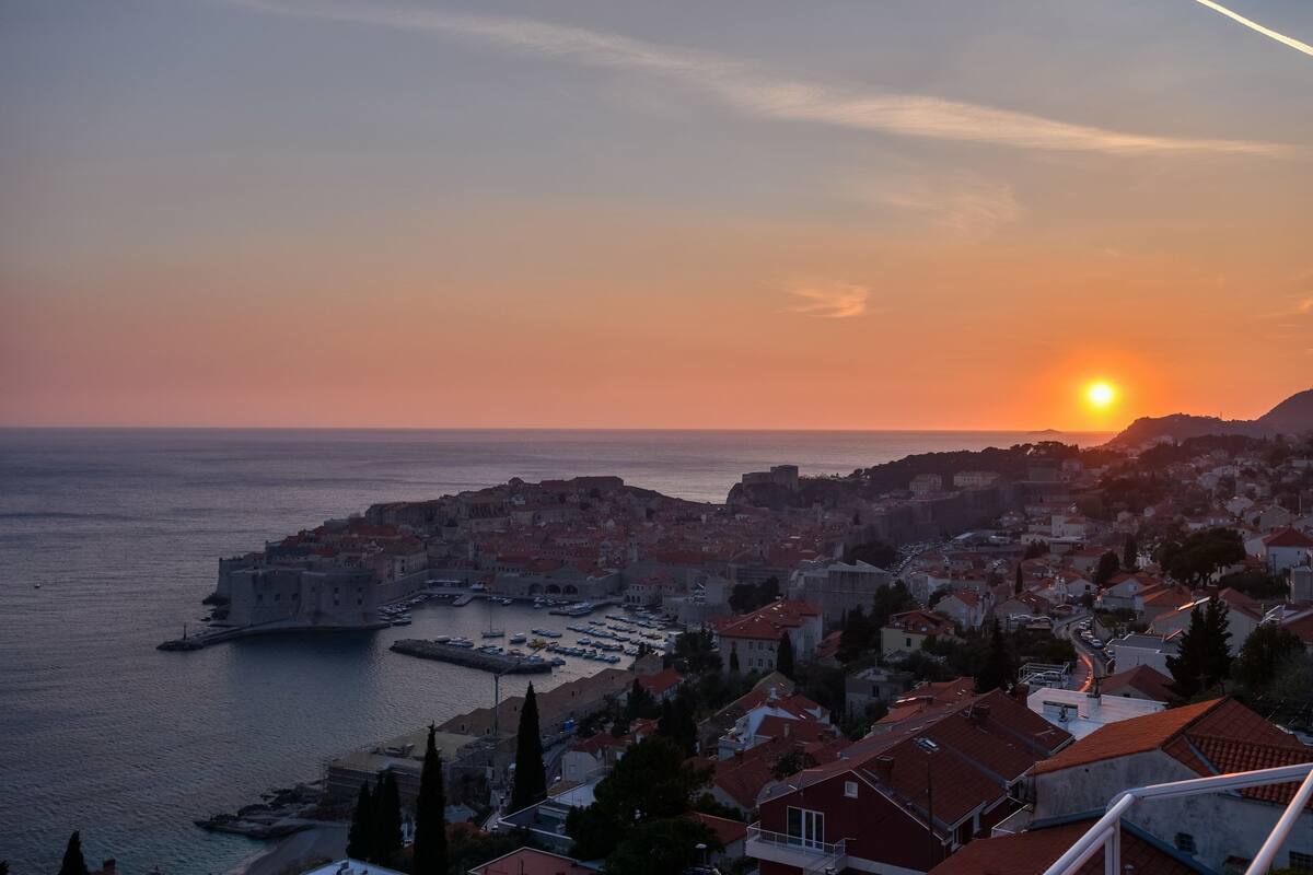 A coastal cityscape with a prominent historic building by the sea, a marina, and residential areas.